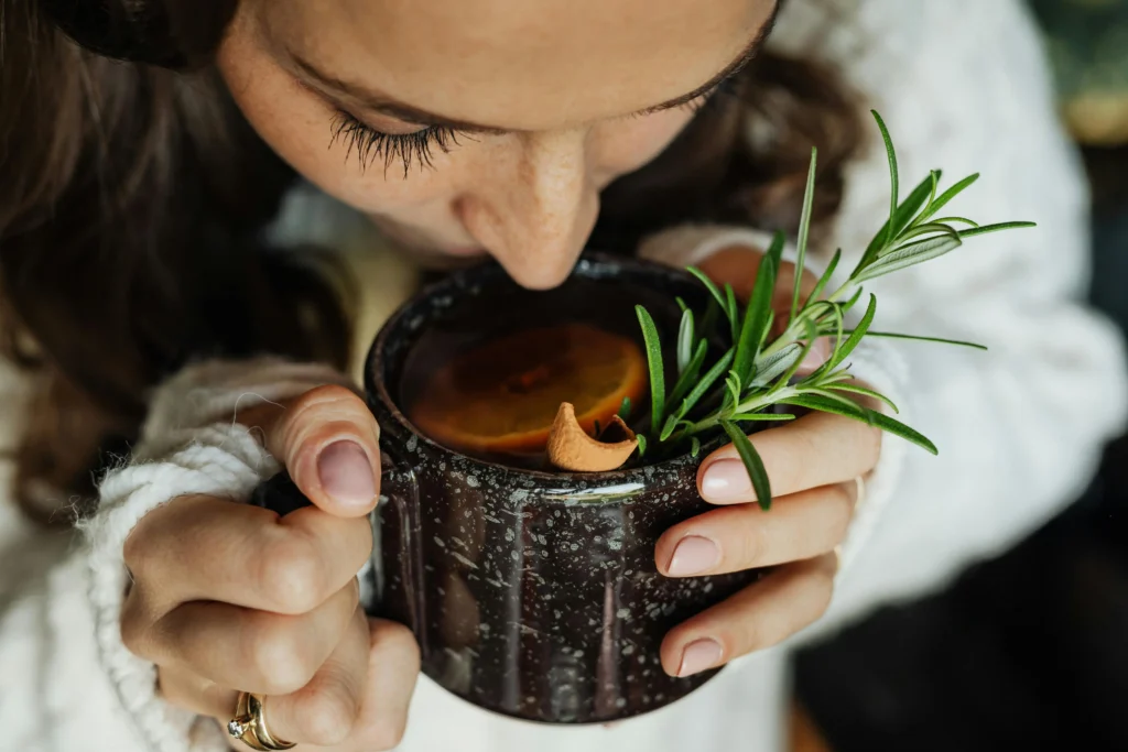 Herbal detox tea with rosemary, citrus, and cinnamon stick in a black speckled mug