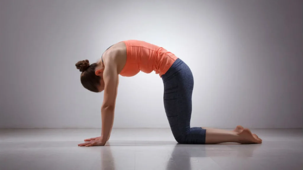 Woman doing Cat-Cow stretch on a mat during somatic Pilates