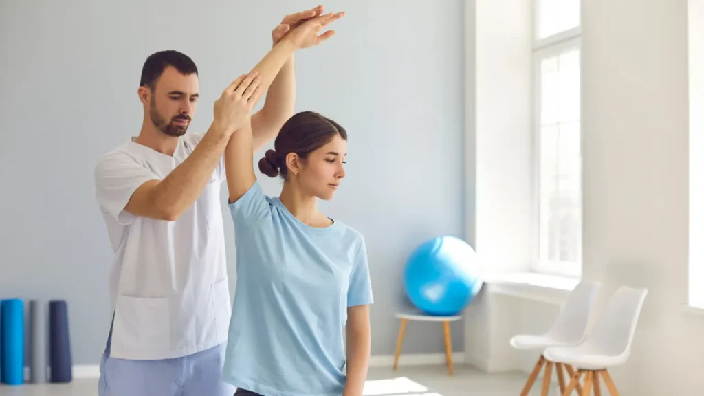 Physiotherapist assisting a young woman in arm rehabilitation therapy for elbow injury recovery.