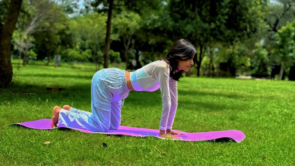 Woman practicing yoga in tabletop pose on a purple mat in a peaceful park after burnout recovery, symbolizing healing after she quit job