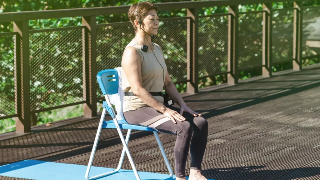 Senior woman practicing chair yoga meditation outdoors